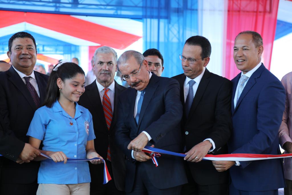  imagen Presidente Danilo Medina de pie cortando cinta junto a Ministro Antonio Peña Mirabal y demás autoridades educativas  en acto inaugural  