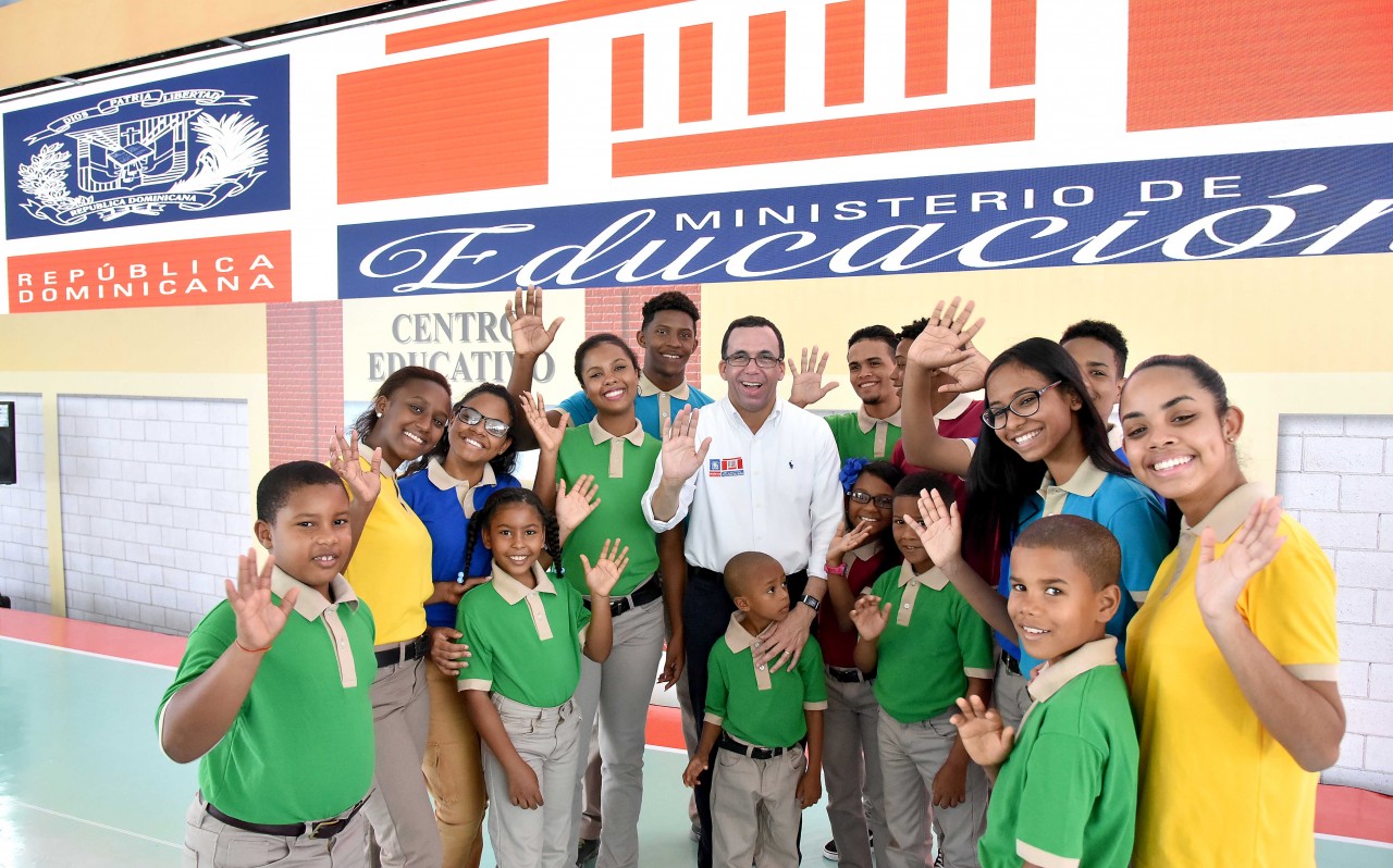  imagen Ministro Andres Navarro junto a estudiantes saludando de pie.Â  