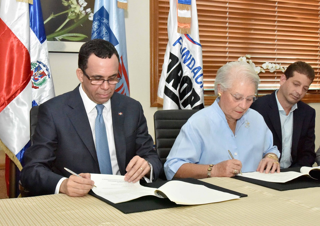  imagen Ministro Andrés Navarro y Margarita Bonetti sentados firmando acuerdo insterintitucional  