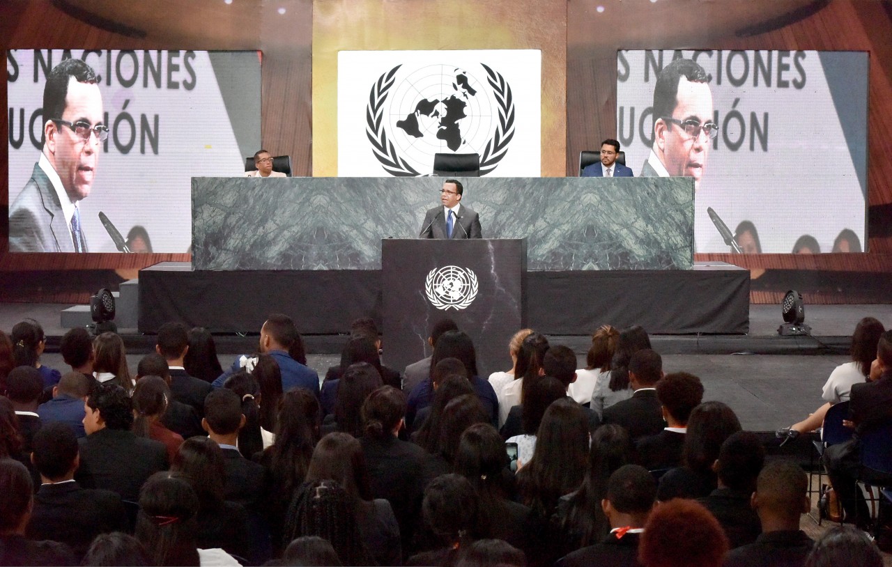  imagen Ministro Andrés Navarro desde podium de pie hablando a mas de 700 estudiantes del programa del Modelo de las Naciones Unidas del Ministerio de Educación 