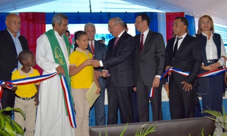  imagen Presidente Danilo Medina de pie cortando cinta junto a Ministro Antonio Peña Mirabal y demás autoridades educativas en acto de entrega de nuevas aulas para Partido en Dajabón  