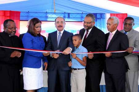  imagen Presidente Danilo Medina mientras corta cinta en acto de inauguración, le acompañan varias personalidades. 
