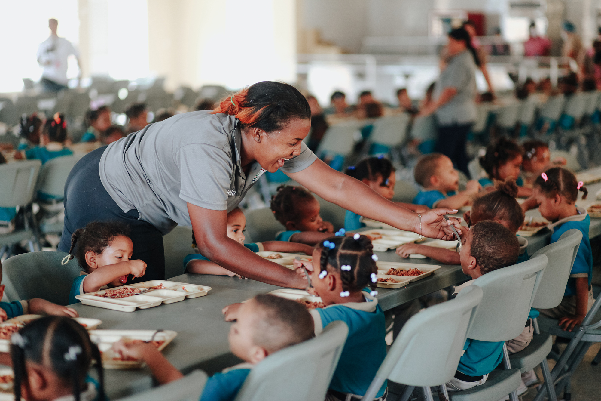 imagen de maestra auxialiando a niños durante almuerzo