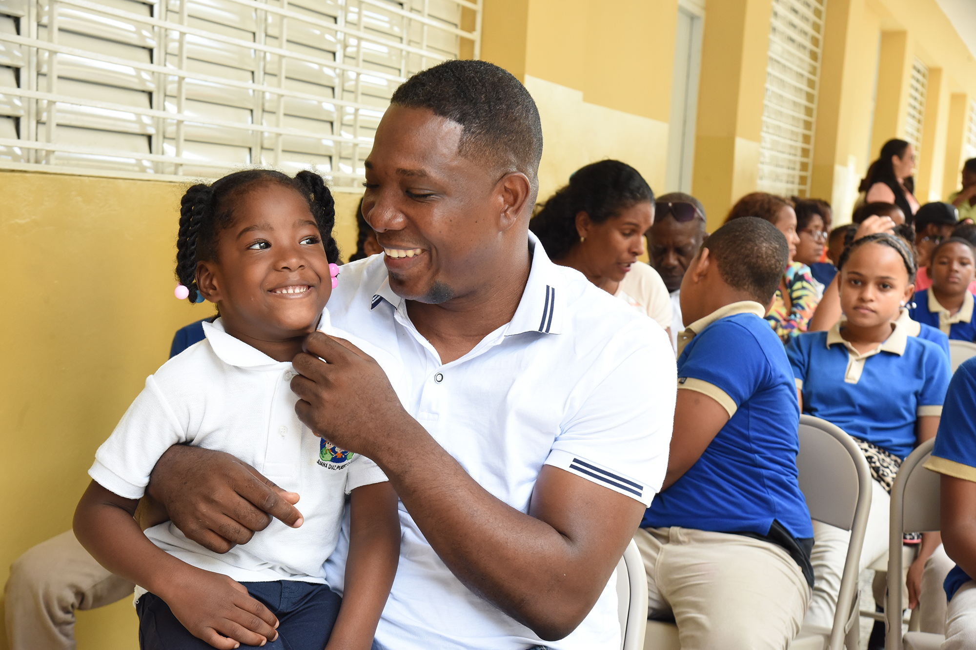 imagen de padre sonriendo con su hija sobre las piernas