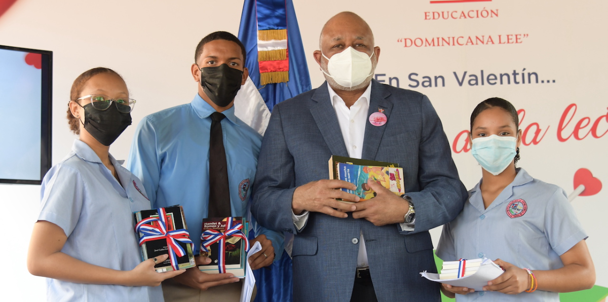  imagen Ministro junto a tres estudiantes posan mientras sostienen libros. 