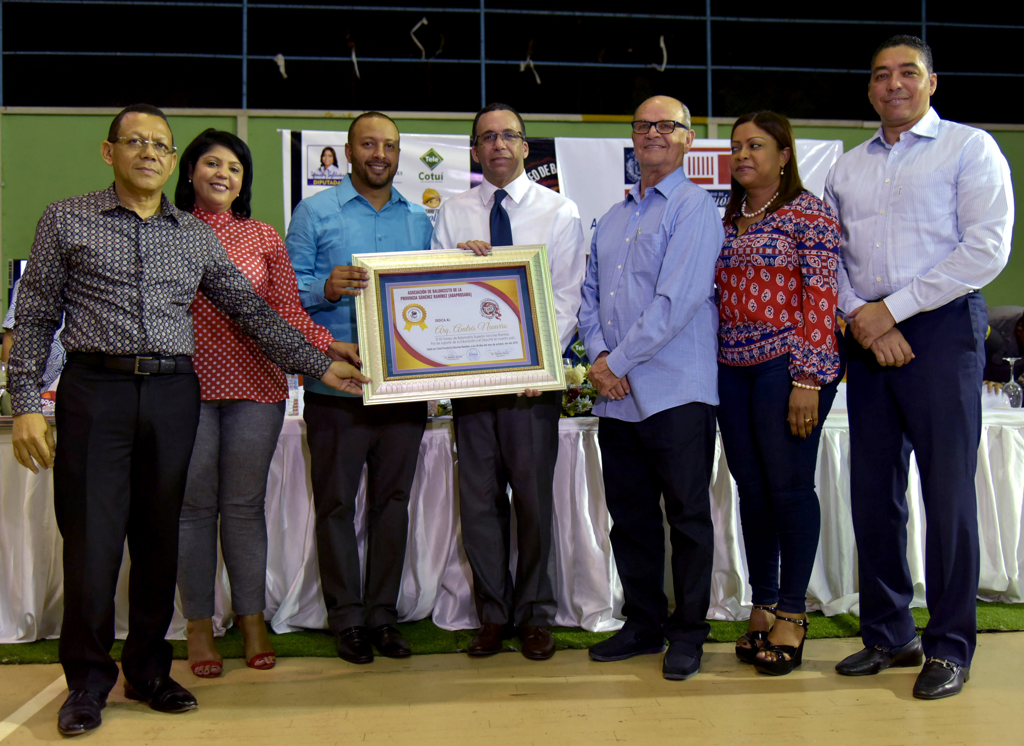  imagen Ministro Andr&eacute;s Navarro de pie sosteniendo bal&oacute;n de basketbal junto a estudiantes y representantes de la Asociaci&oacute;n de Baloncesto de S&aacute;nchez Ram&iacute;rez
&nbsp; 